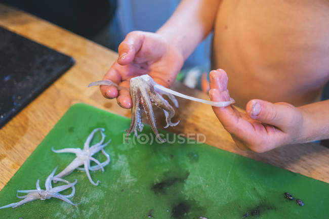 Primer plano de chicos manos limpieza calamar tentáculos - foto de stock
