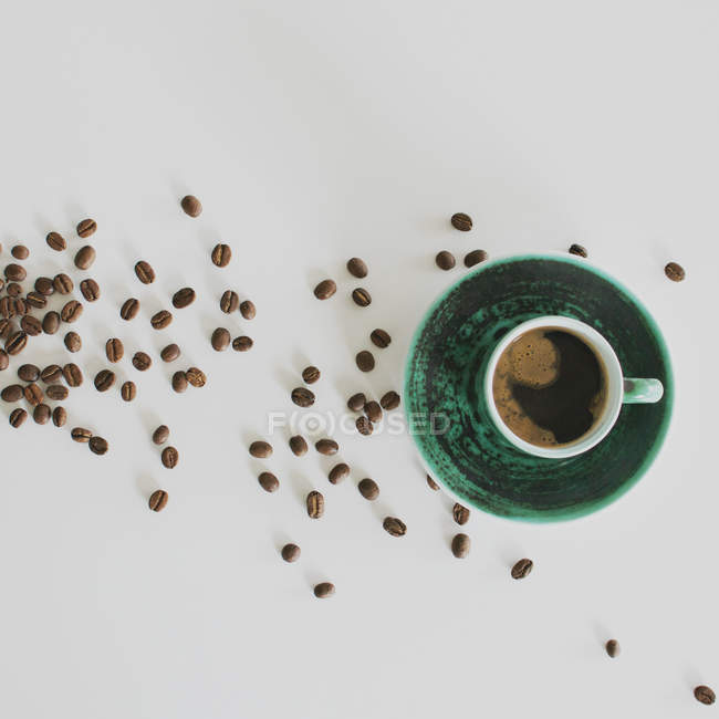 Grãos de café e xícara de café no fundo branco — Fotografia de Stock