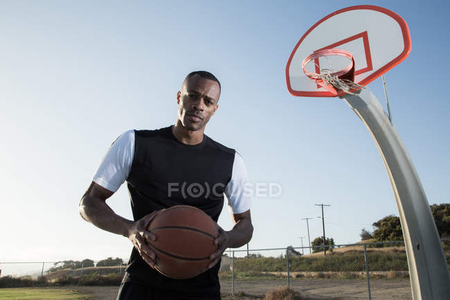 Портрет молодого человека, держащего баскетбольный мяч в парке — стоковое фото