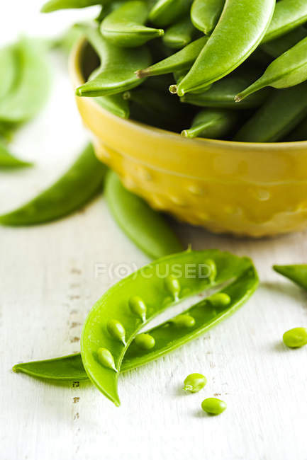 Pois verts frais dans un bol sur une table en bois — Photo de stock