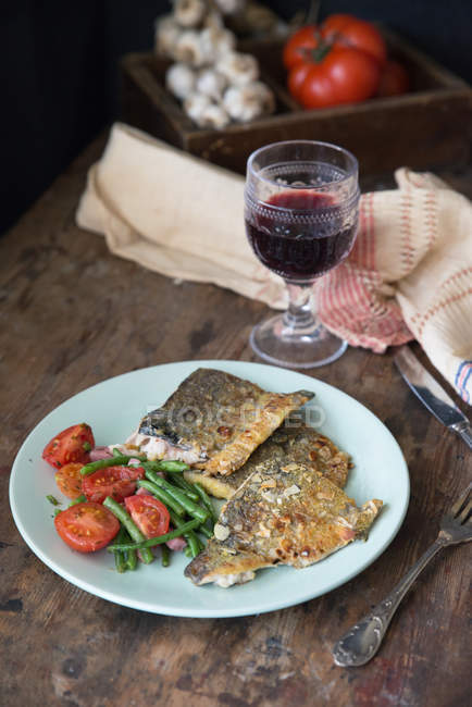Fish with tomato, green beans and a glass of red wine — Stock Photo