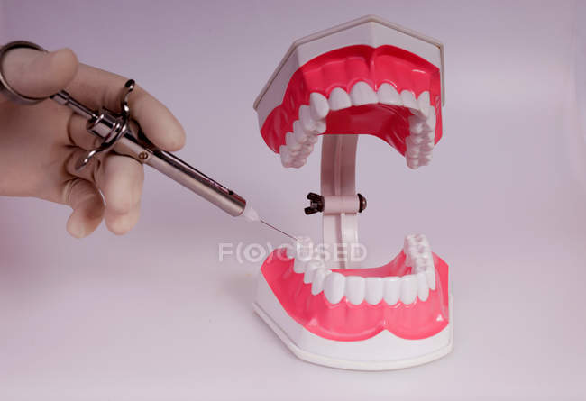 Imagem recortada de mão fazendo injeção para dentaduras contra fundo branco — Fotografia de Stock