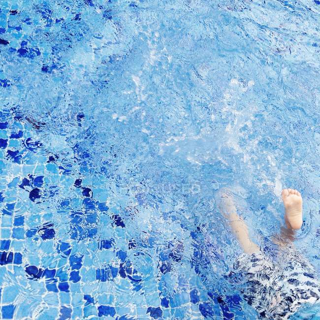 Jambes de garçon éclaboussures dans piscine — Photo de stock