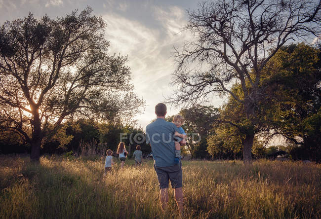 Vater und vier Kinder zu Fuß in der ländlichen Landschaft in der Abenddämmerung, Texas, Amerika, USA — Stockfoto