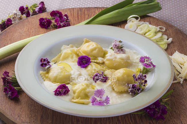 Ravioli with bechamel sauce decorated with flowers — Stock Photo