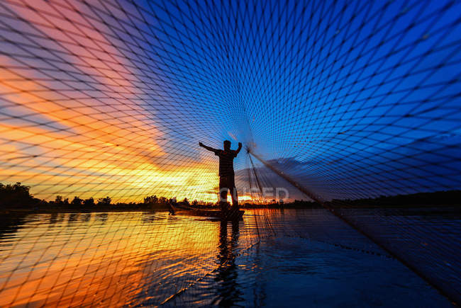 Fisherman casting fishing net al tramonto, Thailandia — Foto stock