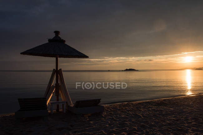 Silhouette di ombrellone e lettini in spiaggia al tramonto, Grecia — Foto stock