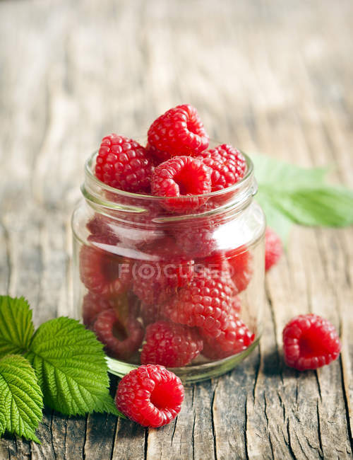 Jar of  fresh and ripe raspberries over wooden table — Stock Photo
