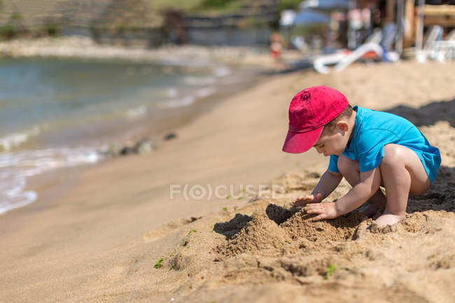 Niño con gorra roja jugando en la playa, Sozopol, Bulgaria - foto de stock