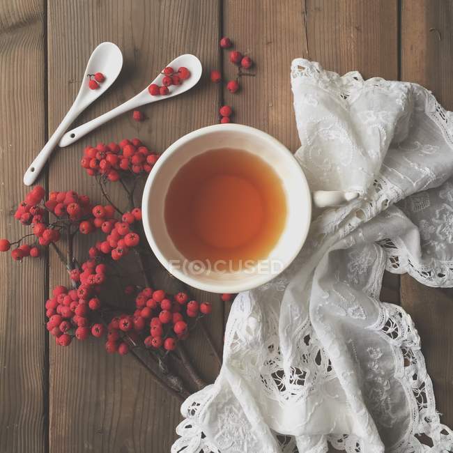 Bayas rojas y té sobre mesa de madera - foto de stock