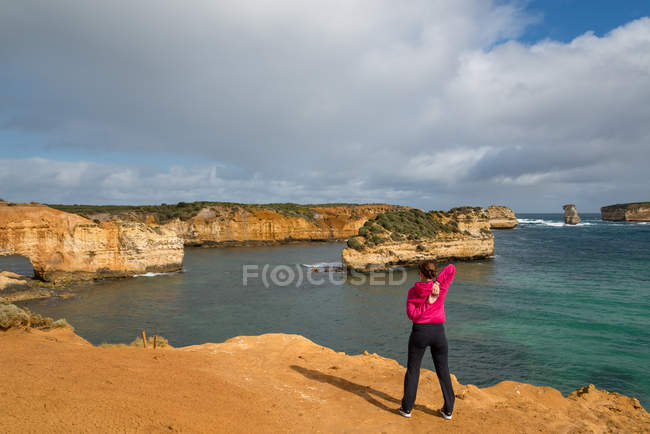 Rear view of woman stretching on coast, Torquay, Victoria, Australia — Stock Photo