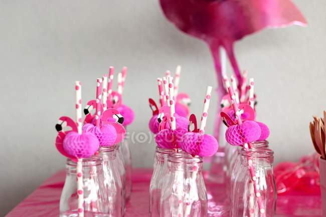 Pink flamingo straws in glass bottles in a row — Stock Photo