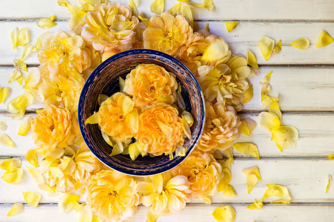 Gelbe Rosen in einer Schüssel auf einem Holztisch — Stockfoto