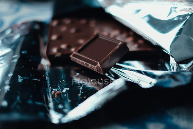 Primer plano de chocolate negro en papel de aluminio, composición simple - foto de stock