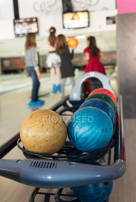 Close-up vista de bolas de boliche com quatro meninas no fundo — Fotografia de Stock