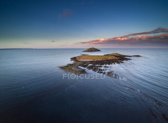 Vista lejana de la isla de ballycotton con faro, Cork, Irlanda - foto de stock