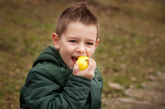 Retrato de niño usando chaqueta comiendo manzana - foto de stock