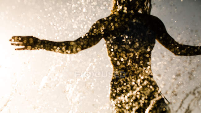 Силуэт женщины-серфера с капельками воды на солнце — стоковое фото