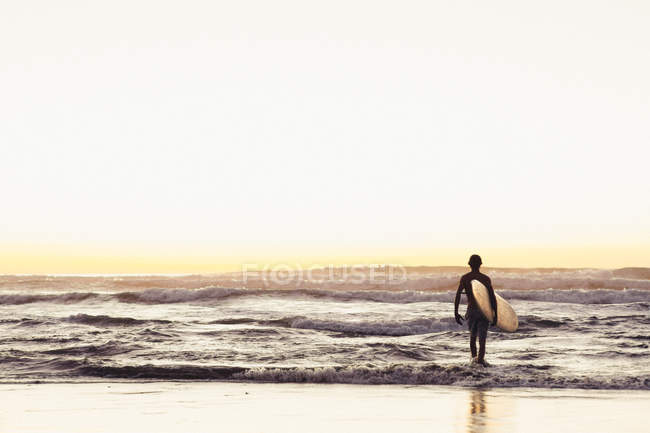 Silhouette del surfista che cammina nell'oceano con tavola da surf, California, America, USA — Foto stock