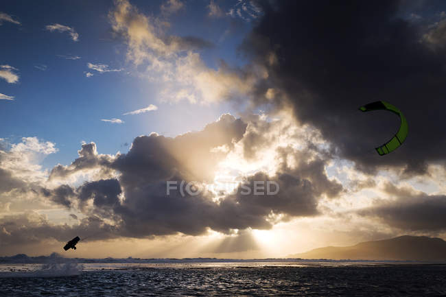 Silhueta de kite-surfista no céu nublado sobre o mar — Fotografia de Stock