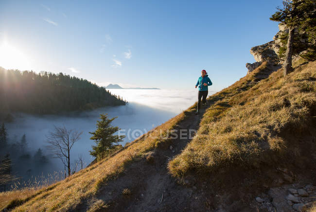 Sendero de mujeres corriendo en las montañas sobre las nubes, Salzburgo, Austria - foto de stock