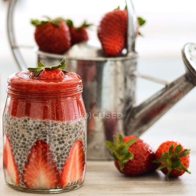 Graines de chia et petit déjeuner aux fraises dans un bocal en verre sur une table en bois — Photo de stock