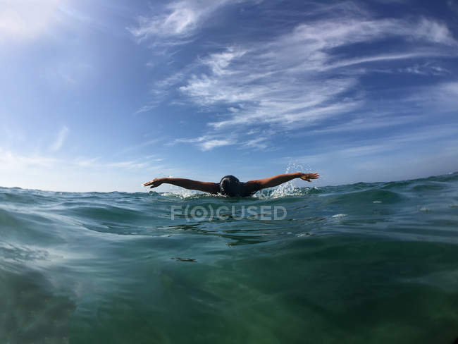 Donna che nuota nell'oceano con cielo nuvoloso sullo sfondo — Foto stock