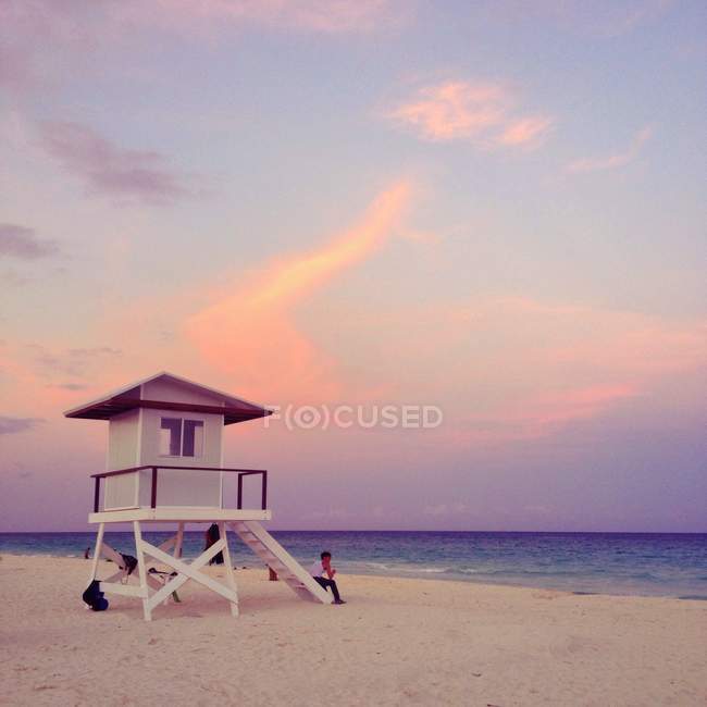 Torre de salva-vidas em pé ao pôr-do-sol com guardião — Fotografia de Stock