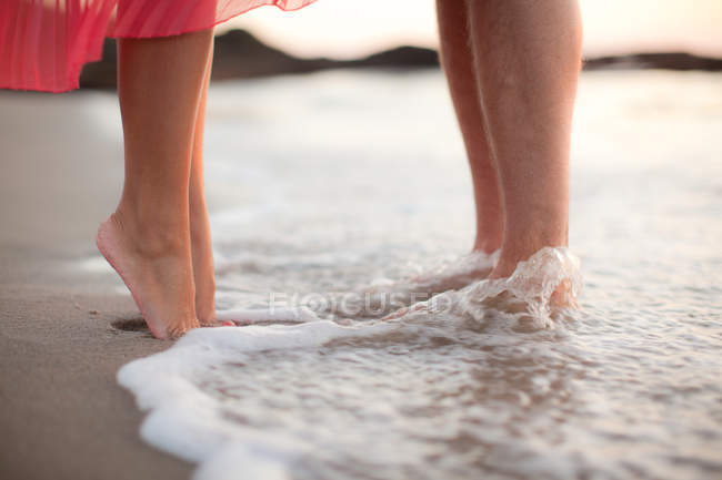 Cropped image of Couple standing in water on beach — Stock Photo