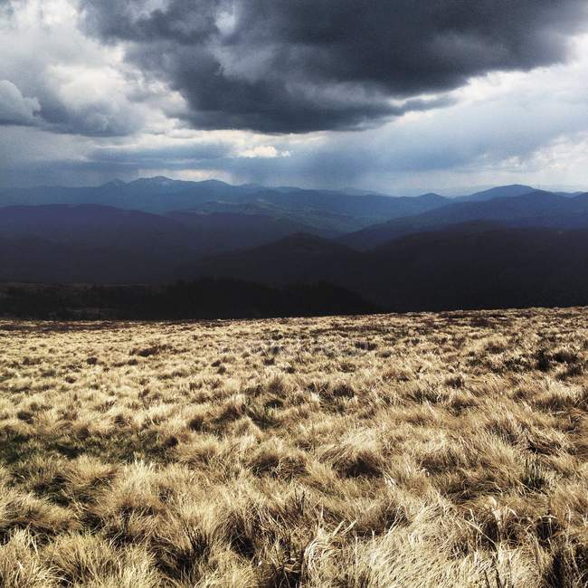 Vista panorâmica da nuvem pesada sobre o campo e montanhas — Fotografia de Stock