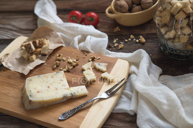 Cheese with croutons and walnuts over wooden table — Stock Photo