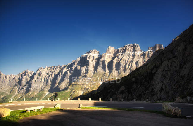 Hombre de pie en la carretera y mirando a la vista, Susten, Suiza - foto de stock