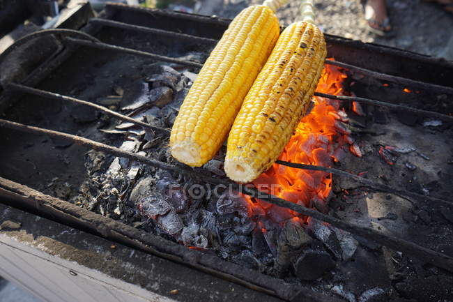 Pannocchie di mais arrosto in fiamme sul barbecue, primo piano — Foto stock