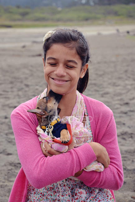 Улыбающаяся девочка-подросток обнимает щенка — стоковое фото