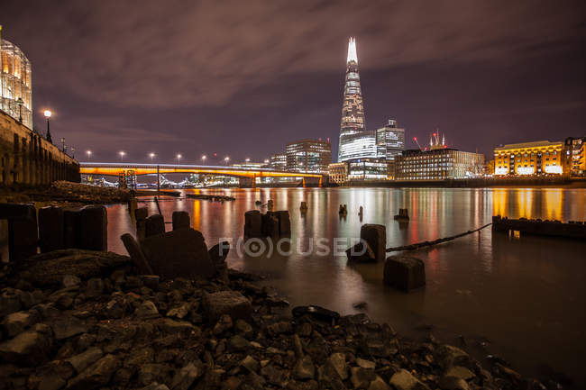 Prédios da cidade iluminados à noite, Rio Tamisa, Londres, Reino Unido — Fotografia de Stock