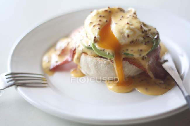 Tasty juicy eggs benedict on white plate — Stock Photo