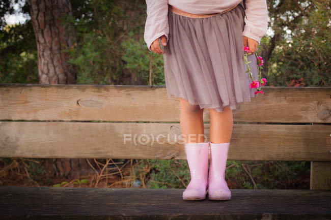 Low section of Girl wearing pink rubber boots holding wreath — Stock Photo