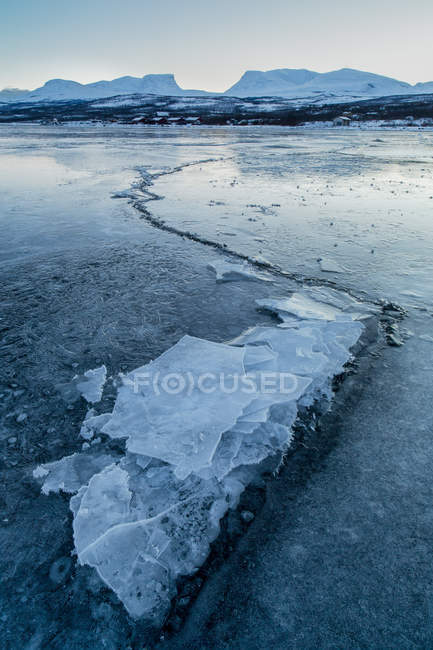 Sweden, Lapland, Frozen Lake of Tornetrask with crack leading to Mountain of Lapporten — Stock Photo