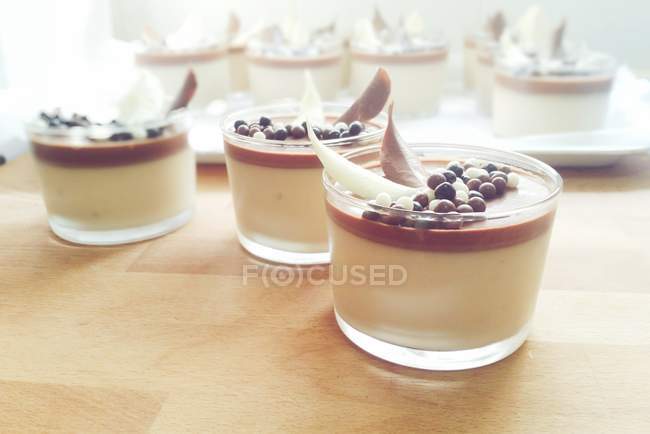 Panelas de nougat e sobremesa de chocolate sobre mesa de madeira — Fotografia de Stock