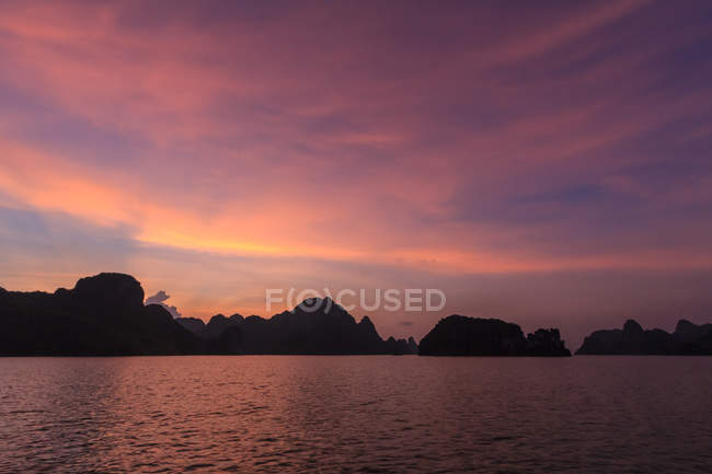 Silueta de kársticos de piedra caliza al atardecer, Bahía Ha long, Vietnam - foto de stock