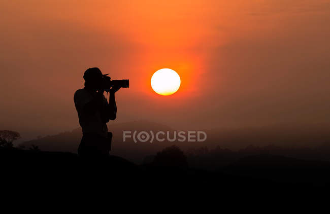 Silhouette d'un homme prenant une photo au coucher du soleil — Photo de stock