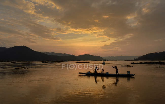 Silueta de dos pescadores en barco en el río Mekong, Tailandia - foto de stock