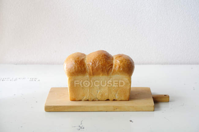 Laib frisch gebackenes Brot auf Holzschneidebrett — Stockfoto