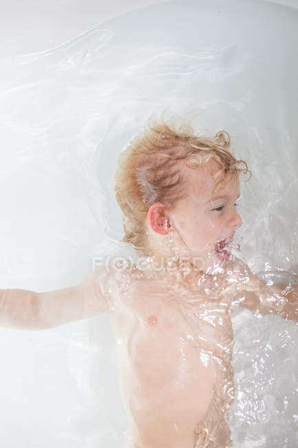 Маленький хлопчик лежить у воді у ванній — стокове фото