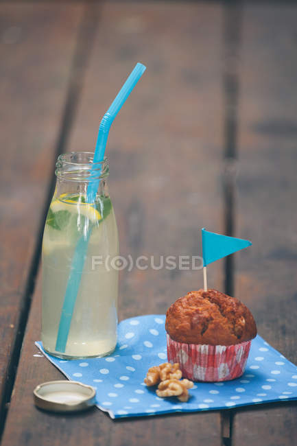 Muffin, nozes e garrafa de limonada na mesa de madeira — Fotografia de Stock