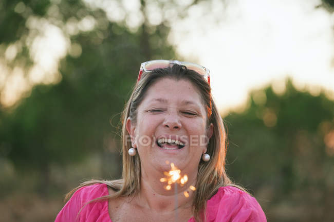Ritratto di una donna felice di mezza età che tiene scintillante e ride — Foto stock