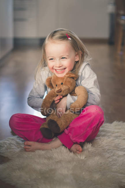 Дівчина сидить на підлозі і обіймає плюшевого ведмедя — стокове фото