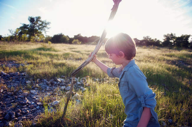 Хлопчик тримає дерев'яну палицю в природі — стокове фото