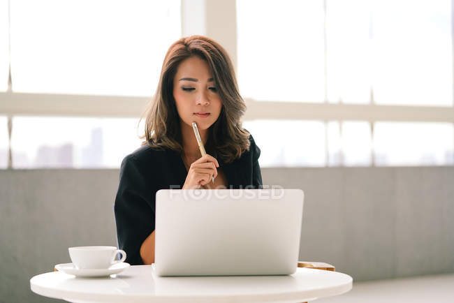 Бізнес-леді сидить в офісі і працює з ноутбуком — стокове фото