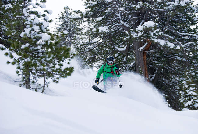 Homem esquiando na encosta com árvores no inverno — Fotografia de Stock